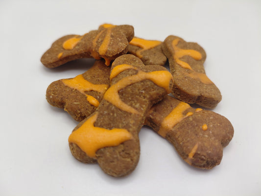Dog treats shaped like bones with orange drizzle on a white background