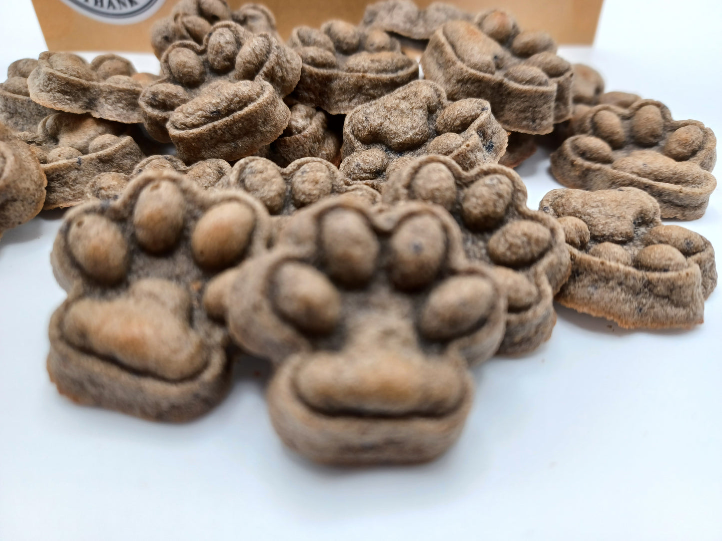 Liver + Blueberry Dog Treats shaped like paw prints on a white surface