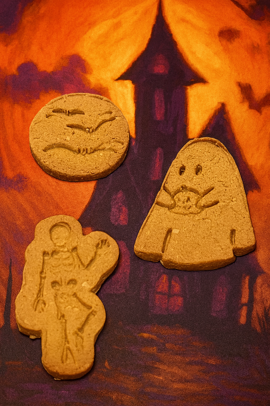 Spooky Peanut Butter Bones. Handmade organic dog treats from The Chosen Spot K9 Kitchen on a haunted house background.
