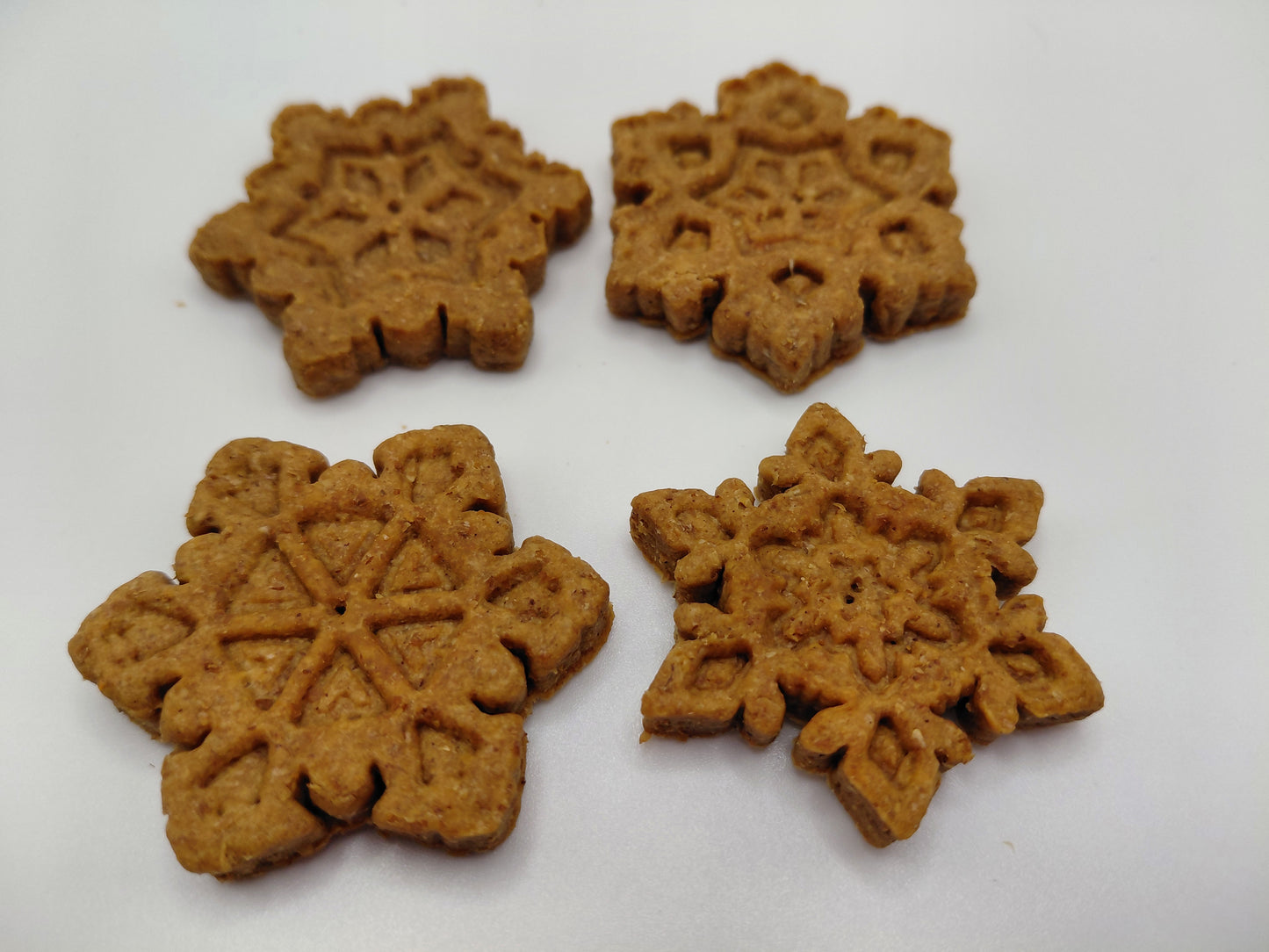 Four Peanut Butter Snowflakes, handmade organic dog treats from The Chose Spot K9 Kitchen on a white background