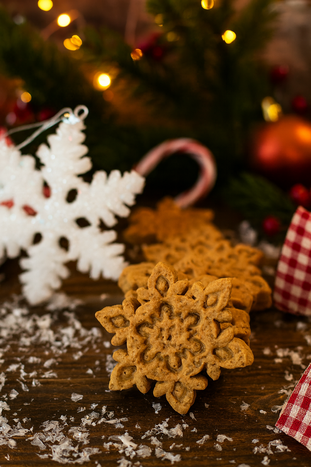Peanut Butter Snowflakes from The Chosen Spot K9 Kitchen on a wooden surface with Christmas decorations in the background.